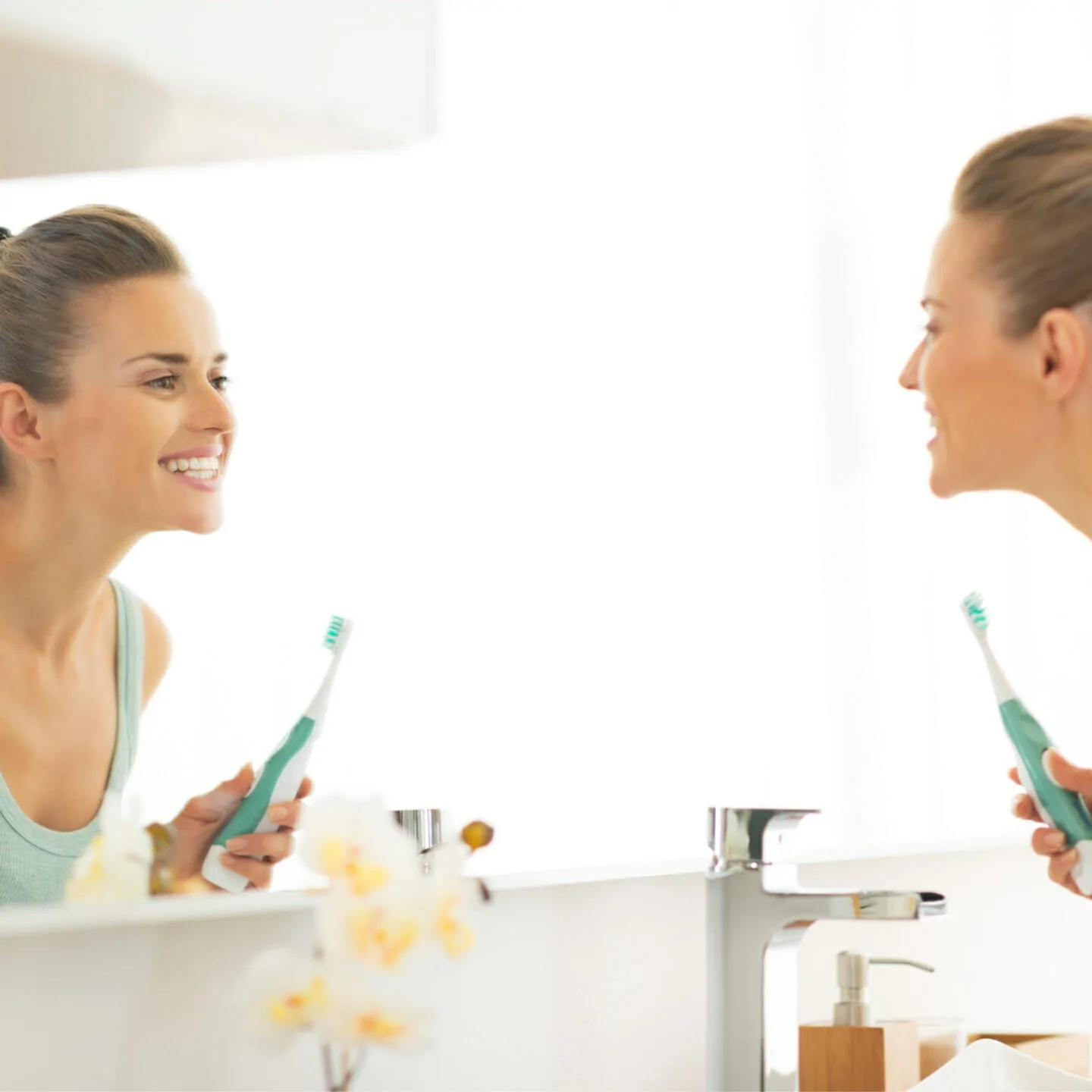 Young woman looking in mirror after brushing teeth